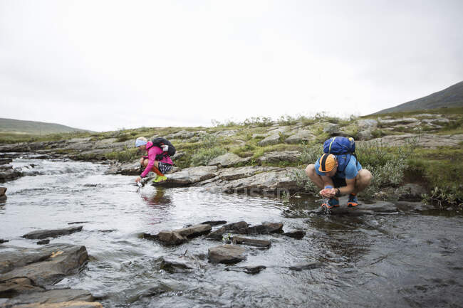 Couple drinking water from stream while hiking — Foto stock