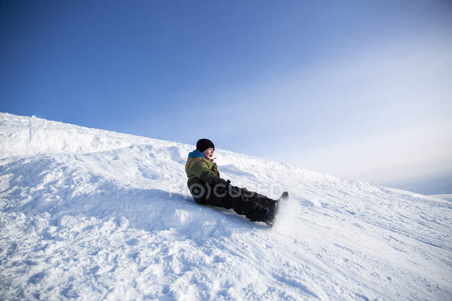 Boy sledding on mountain — Stock Photo