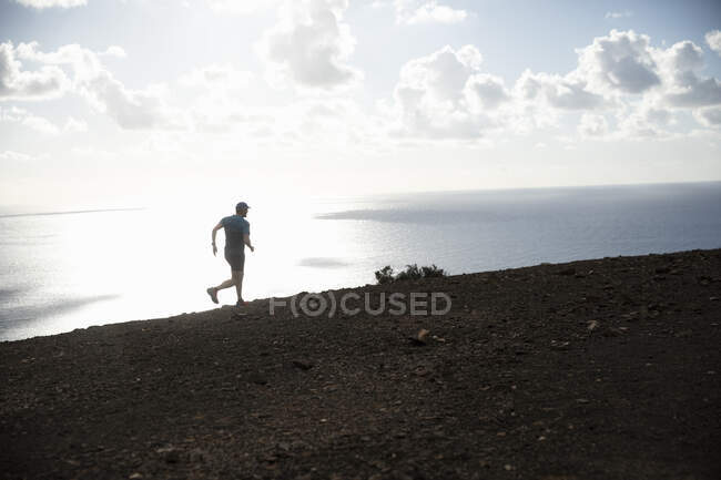Homem correndo na montanha por costa — Fotografia de Stock