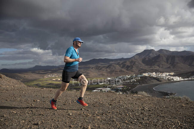 Man jogging on mountain by coast — Foto stock