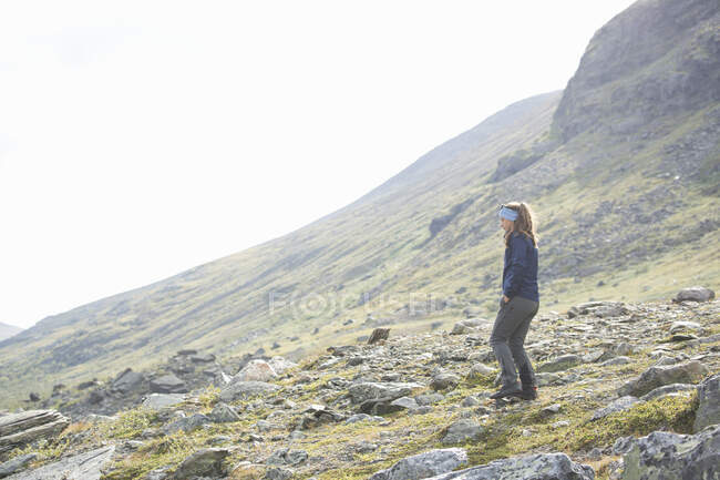 Mulher de pé na montanha enquanto caminhadas — Fotografia de Stock