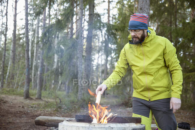 Homme allumant feu de camp dans la forêt — Photo de stock