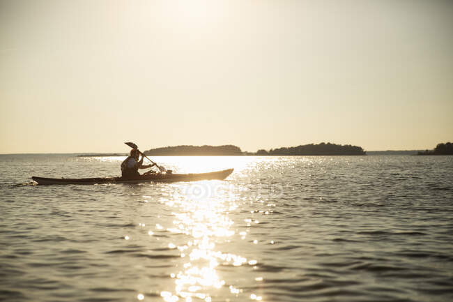 Homme kayak sur la mer au coucher du soleil — Photo de stock