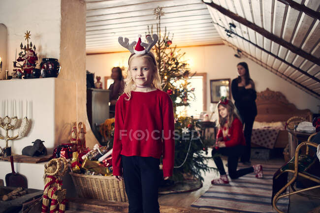 Menina usando headband de Natal pela árvore de Natal — Fotografia de Stock
