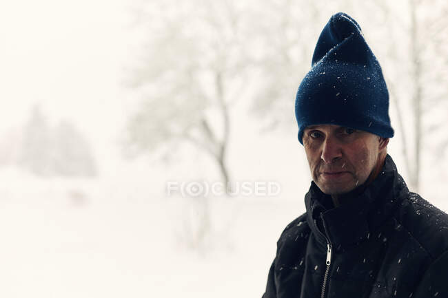 Portrait of mature man wearing beanie in snow — Stock Photo