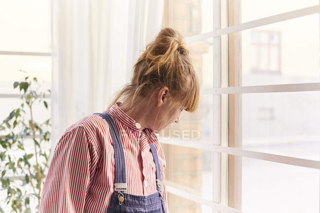 Donna dai capelli rossi che indossa camicia a righe dalla finestra — Foto stock