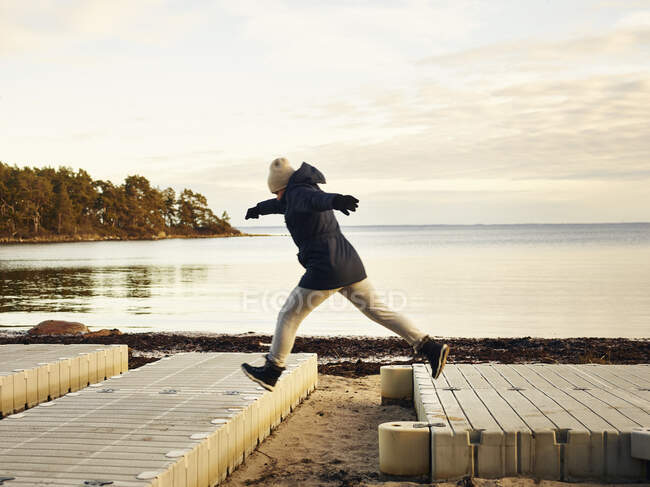 Frau springt am Strand zwischen Stegen — Stockfoto