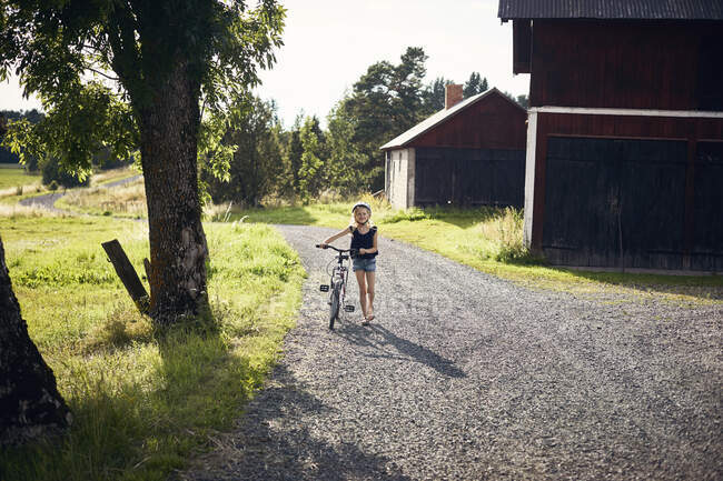 Mädchen läuft mit Fahrrad auf Landstraße — Stockfoto