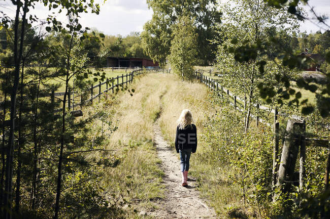 Chica caminando en granja sendero - foto de stock