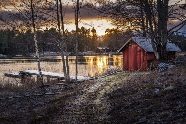 Cabin by lake at sunset — Stock Photo