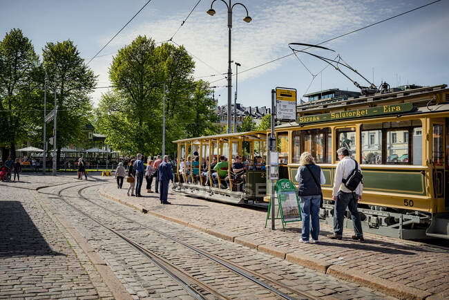 Peatones y tranvía en la calle de la ciudad en Helsinki, Finlandia - foto de stock