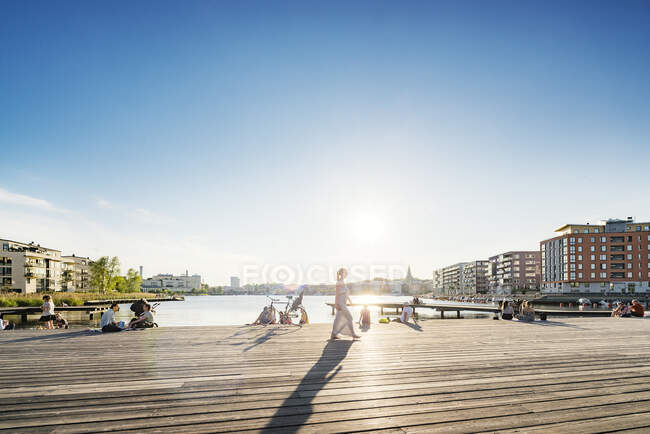 Personas en el paseo marítimo al atardecer en Estocolmo, Suecia - foto de stock