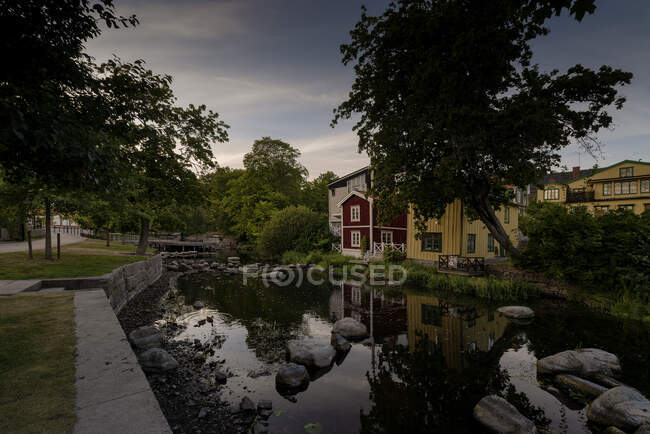 Река, деревья и дома на закате — стоковое фото
