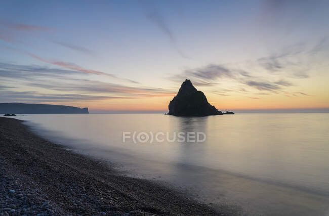 Silhueta de formação rochosa no mar durante o pôr do sol — Fotografia de Stock