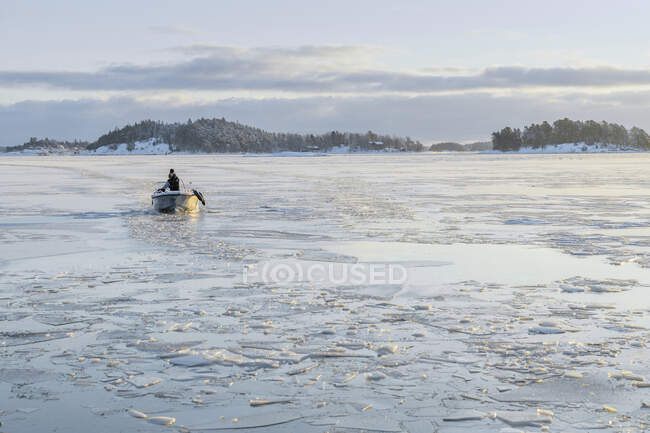 Hombre en barco en el mar congelado - foto de stock