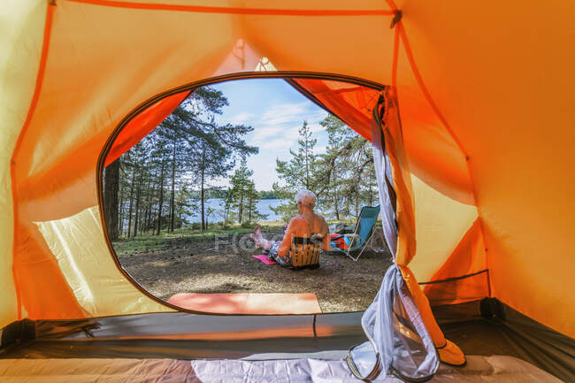 Senior woman sitting by tent — Stock Photo