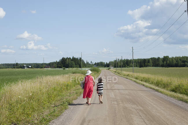 Жінка йде з онукою по сільській дорозі — стокове фото