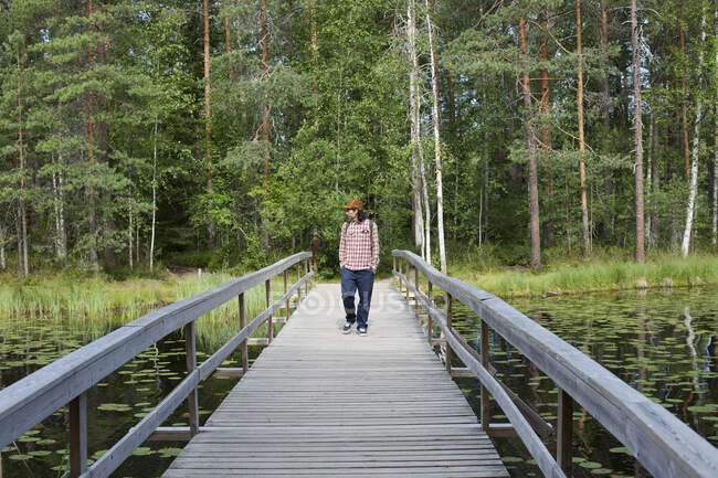 Hombre caminando sobre el puente sobre el lago - foto de stock