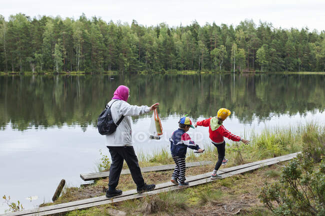 Femme marchant avec ses petits-enfants par la rivière — Photo de stock