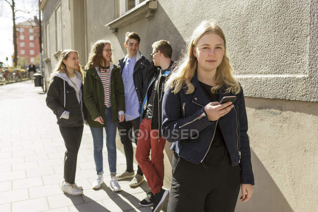 Giovane donna in possesso di smart phone dai suoi amici a Stoccolma, Svezia — Foto stock