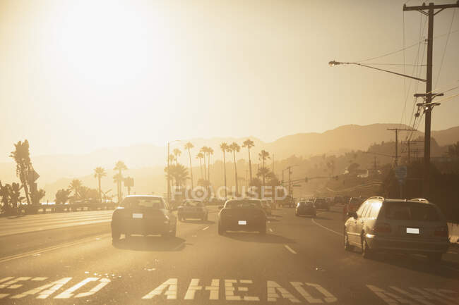 Автомобілі, що їздять по дорозі на заході сонця — стокове фото