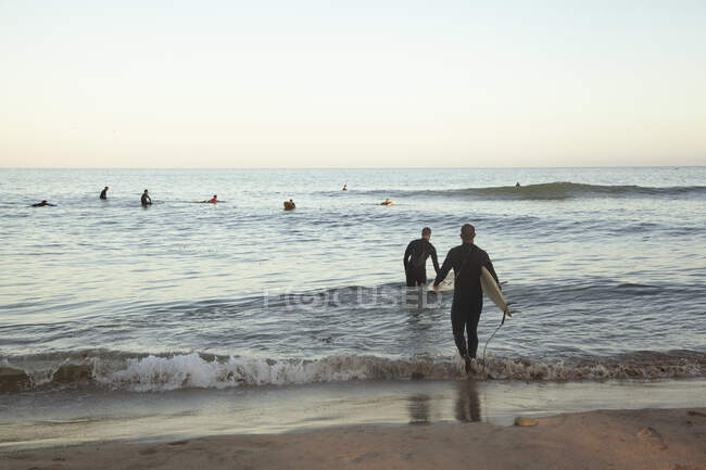 Люди занимаются серфингом на море на закате — стоковое фото