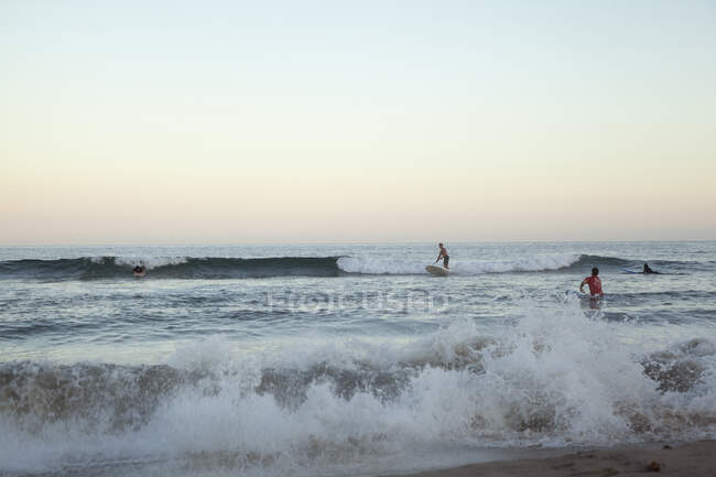 Pessoas surfando no mar ao pôr do sol — Fotografia de Stock