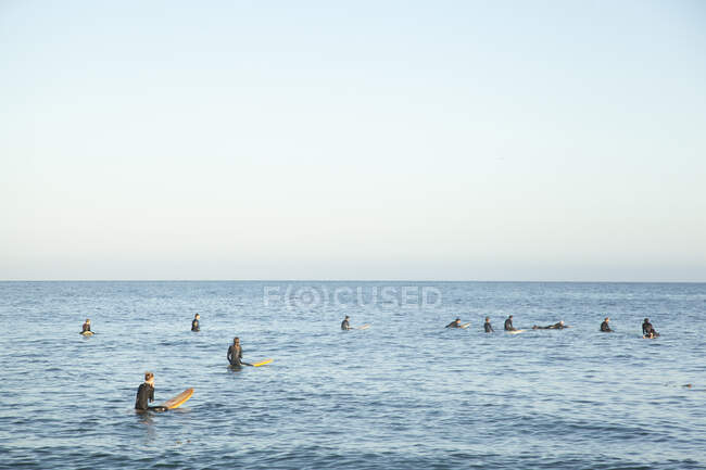 Люди занимаются серфингом на море на закате — стоковое фото