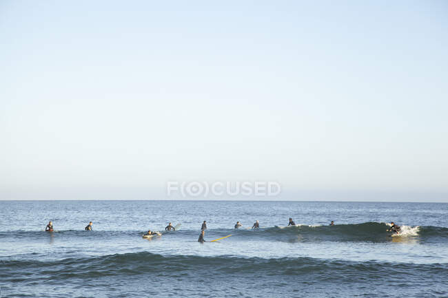 Menschen surfen bei Sonnenuntergang auf dem Meer — Stockfoto