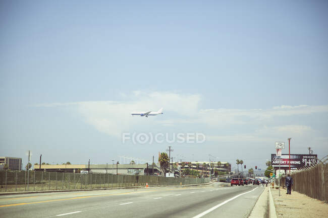 Airplane flying over city highway — Stock Photo