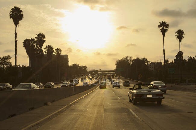 Voitures conduisant sur 101 Freeway au coucher du soleil à Los Angeles, Californie — Photo de stock