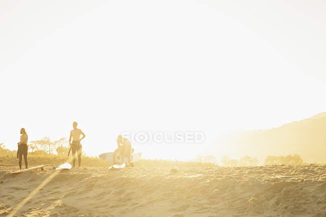 Surfeurs sur la plage au coucher du soleil — Photo de stock