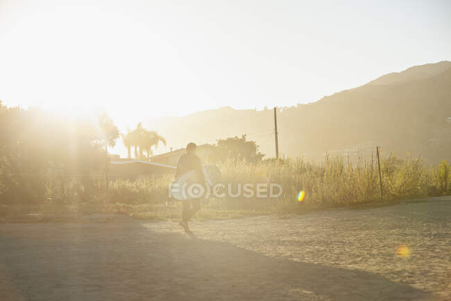 Mann trägt Surfbrett bei Sonnenuntergang — Stockfoto