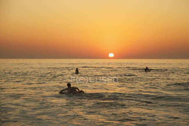 Surfeurs en mer au coucher du soleil — Photo de stock