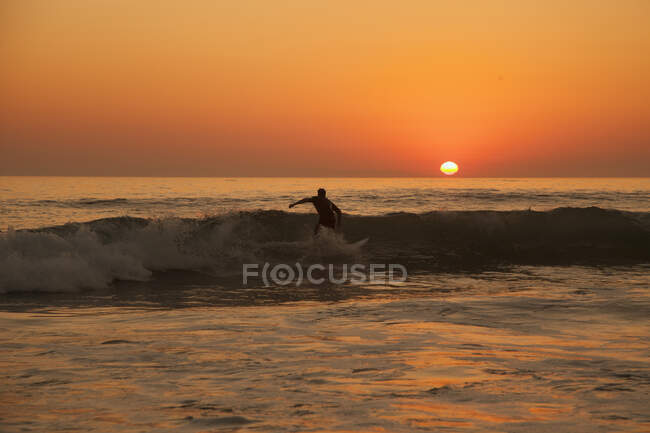 Человек серфинг на пляже Лагуна во время заката — стоковое фото