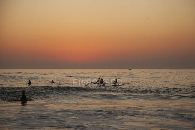 Серфингисты в море на закате — стоковое фото