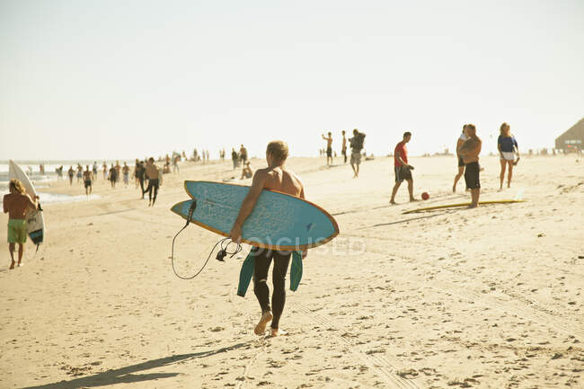 Uomo che trasporta tavola da surf sulla spiaggia — Foto stock