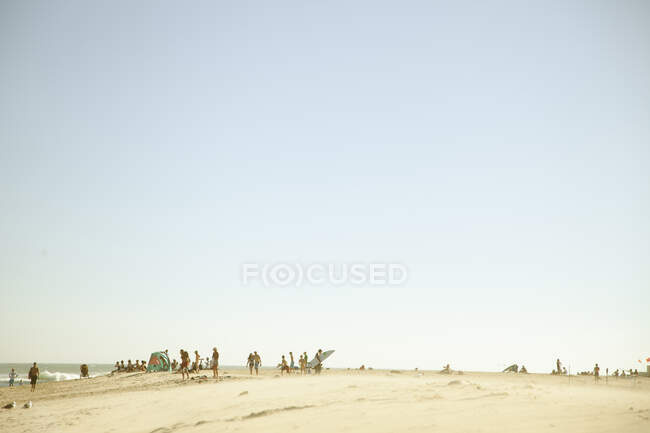 Люди на пляже во время заката — стоковое фото