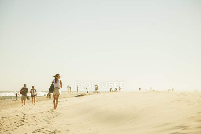 Pessoas andando na praia durante o pôr do sol — Fotografia de Stock