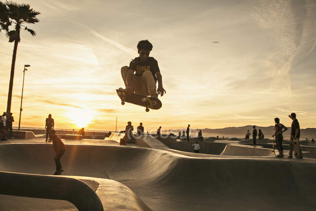Підлітковий хлопчик катається на скейтпарку під час заходу сонця — стокове фото