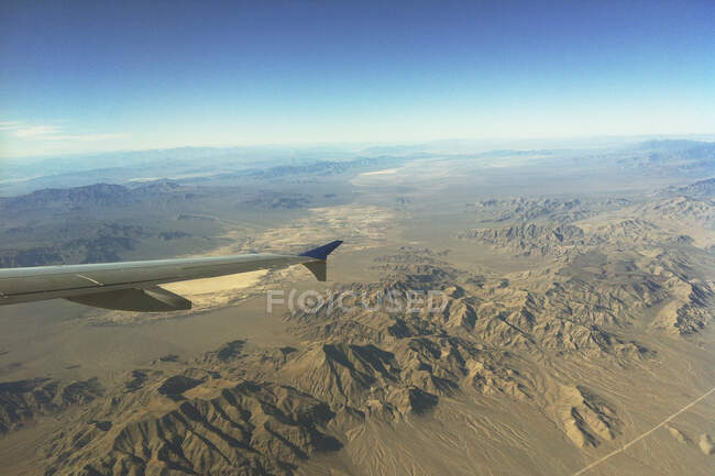 Wing of airplane flying over mountains — Stock Photo