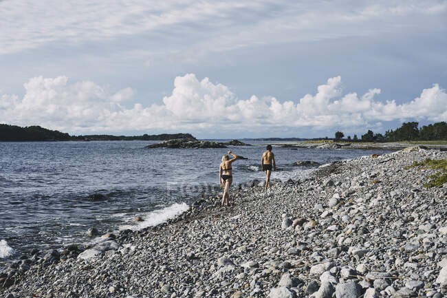 Пара в купальниках, гуляющая по пляжу — стоковое фото