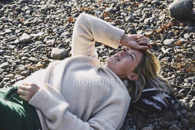 Mulher de camisola deitada na margem do rio — Fotografia de Stock