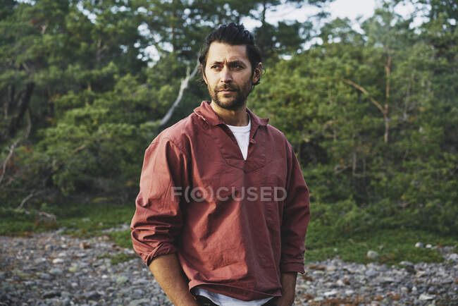 Человек в красной куртке стоит в лесу — стоковое фото