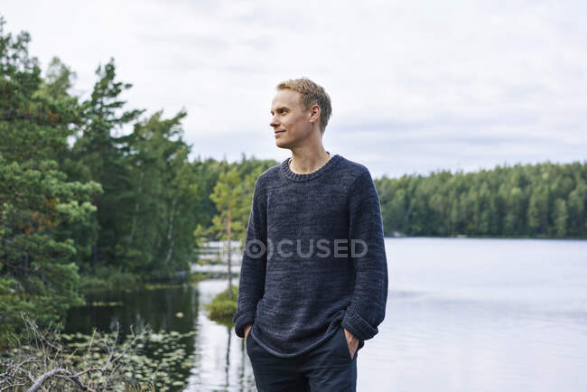Uomo in maglione in piedi vicino al fiume — Foto stock