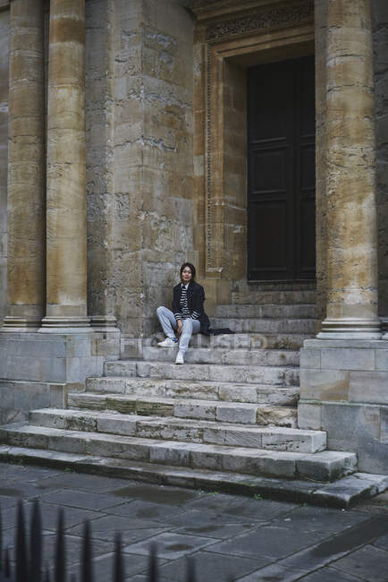 Woman in coat sitting on steps — Stock Photo