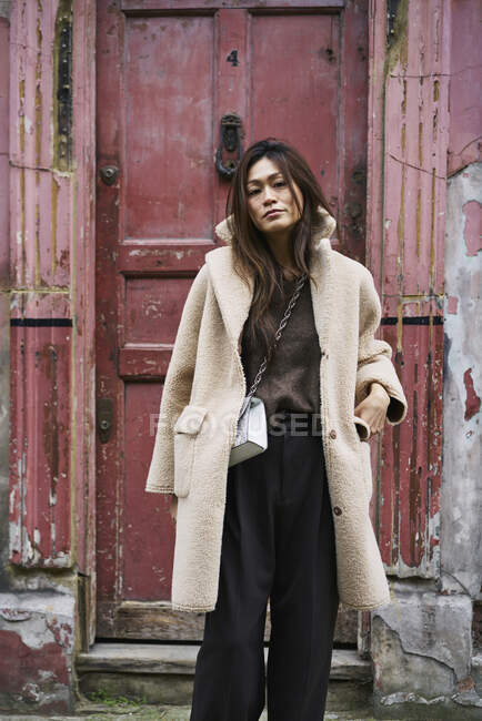 Woman in coat by weathered door — Stock Photo