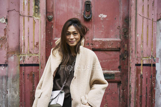 Frau im Mantel vor verwitterter Tür — Stockfoto