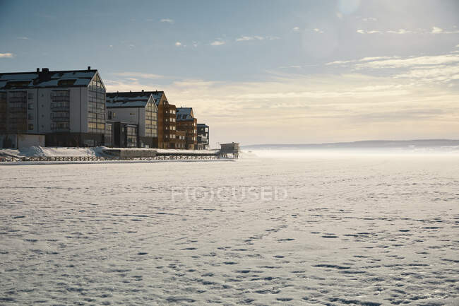 Edifícios por lago congelado no inverno — Fotografia de Stock