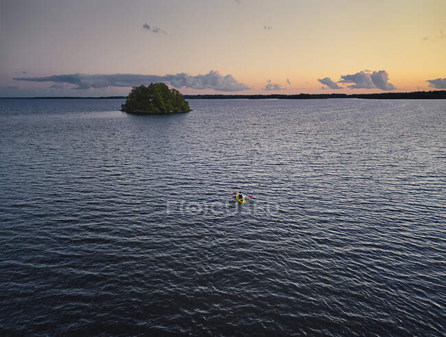 Homem de caiaque no lago durante o pôr do sol — Fotografia de Stock